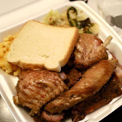 Smoked turkey wing and rib combo plate with macaroni and cheese, smoked cabbage and slice of bread on the side.