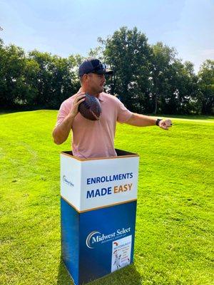 Golfer standing in Midwest Select's employee benefits box getting ready to throw a football for the fowling competition.