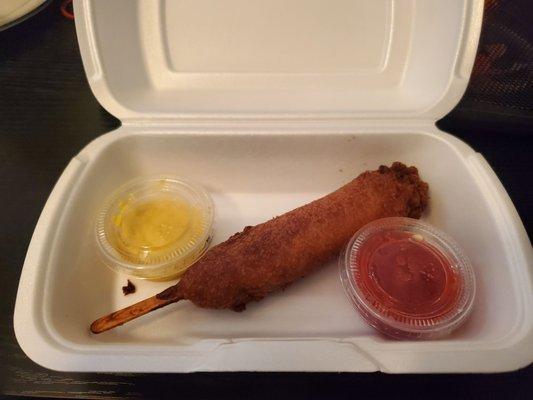 Crispy battered corndog with mustard and ketchup.