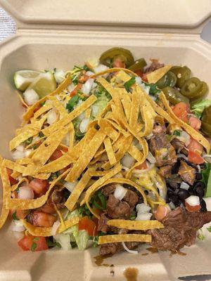 Burrito bowl with carne asada, tortilla chips and jalapeños. Spicy!