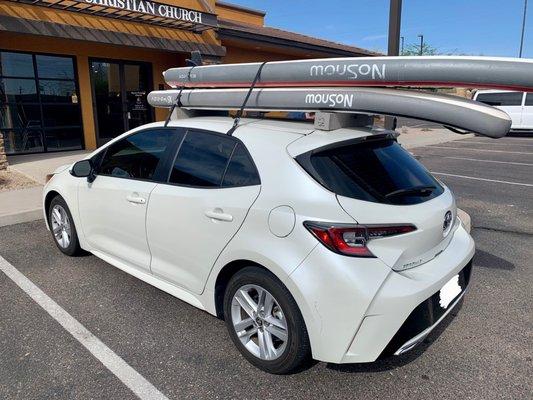 Small car with 2 boards strapped to the roof.