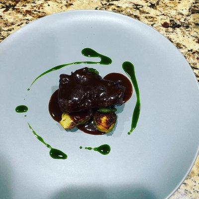 Red wine braised short rib, roasted Brussels sprouts, red wine demi glace, parsley oil.