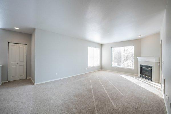 Carpeted living room with fireplace and windows.