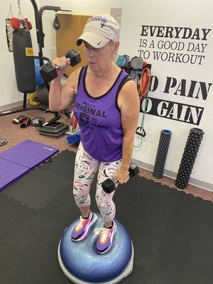 Linda balancing on the Bosu while doing hammer curls to shoulder presses.