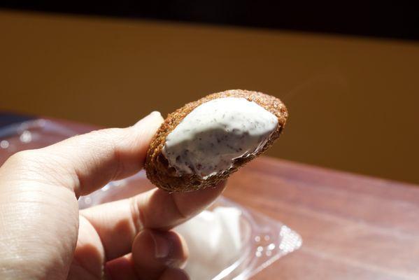 Falafel ball dipped in white sauce.