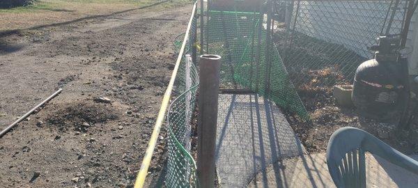 Reinstalled fence post. Note: the yellow tape is tied to the fence posts on either side of this post, which is a foot and a half out of line