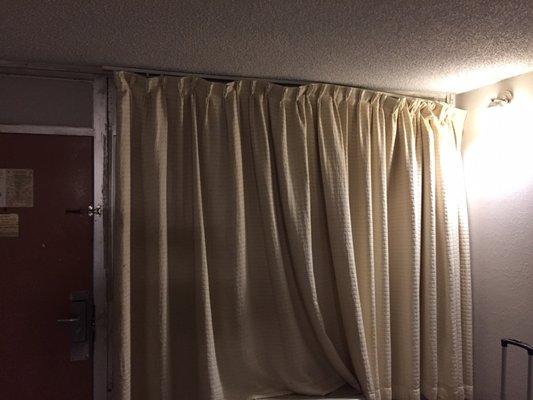 Curtains barely hanging on the rod.