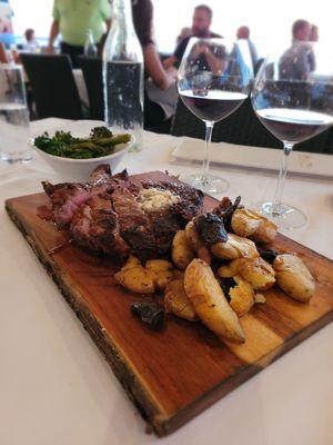 The carnivore's board, a perfect share. | ribeye (20oz, medium) with crisp tender fingerlings and roasted broccolini. Paired with bourbon.