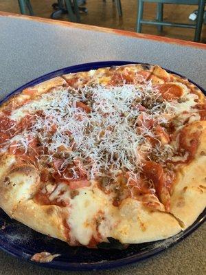 Pizza with Pepperoni, sausage and slices of tomato on it.