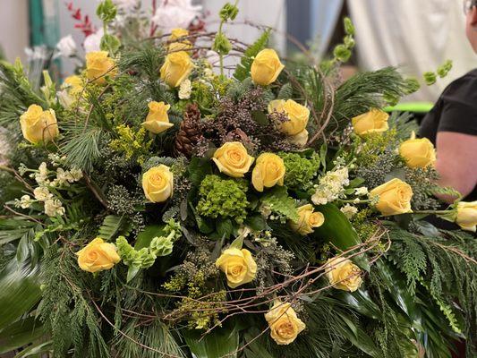 A casket spray with yellow roses with a little twist