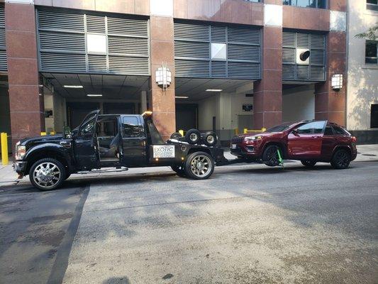 Car being towed downtown Chicago.