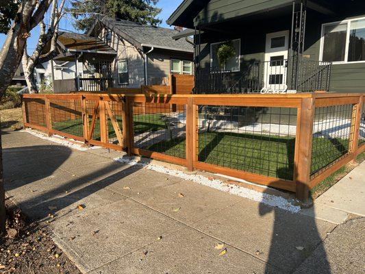 Black hog wire fence with clear cedar fascia and cedar 2x4 top cap