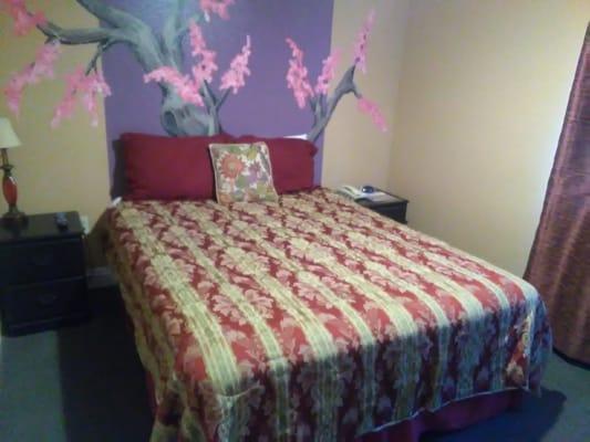 Queen size bed with painted Asian inspired mural on the wall.