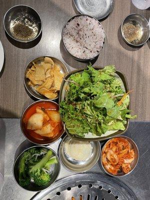 Salad, seafood tofu cake, radish, broccoli, Kim chi, potato salad, purple rice