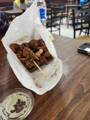 Spicy popcorn chicken. Served with wooden skewers. They don't provide utensils or plates.