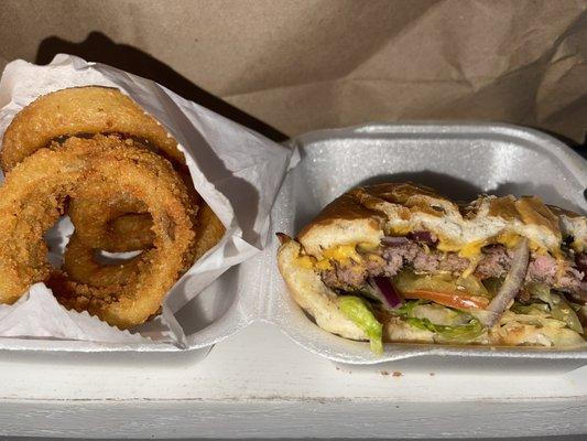 Half eaten cheeseburger and onion rings.