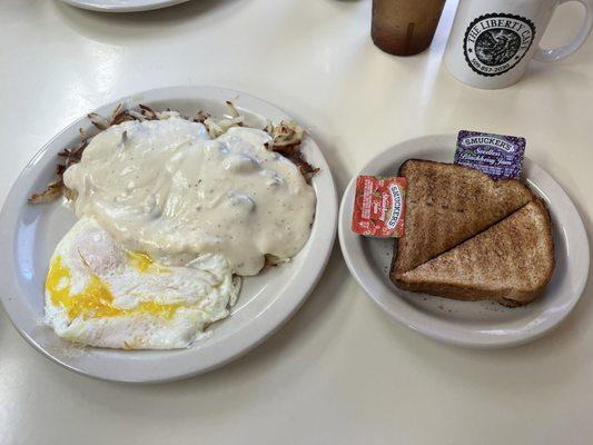 2 egg breakfast with toast and hash browns, sausage gravy on top.