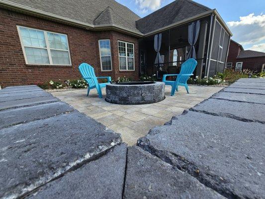 An outdoor living space featuring a paver patio, seating wall and fire pit in Clarksville Tn.