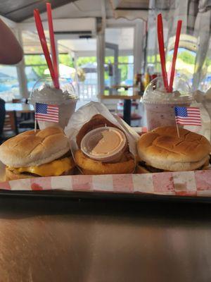 Two cheeseburgers, side of onion rings, blackberry shake (right), oreo shake(left)