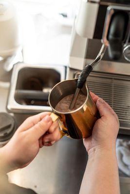 Steaming chocolate milk for a creamy hot cocoa soon to be topped with house made whipped cream!