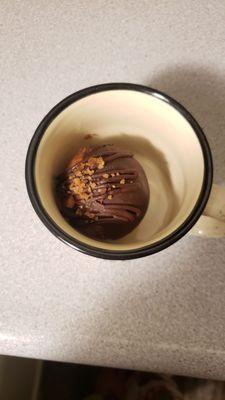 Salted caramel chocolate bomb in a mug for scale, awaiting warm milk