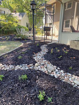 Rainbow rock riverbed with shade loving perennial flowers.