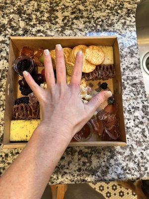 My hand over the box for size comparison. This was a medium charcuterie box that is stated to feed up to 10 people.