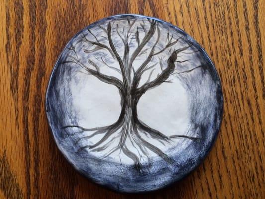 This small plate is a painting of tree in winter with full moon behind it.