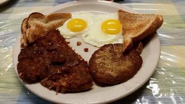 Eggs sunny side up, corned beef hash, sausage patty, and wheat toast