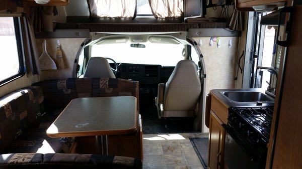 Interior of 2009 Coachmen 22' RV. Dining table folds down into a bed, queen bed over cab with swing-out TV.