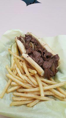 Philly cheese steak sandwich with fries and a pickle