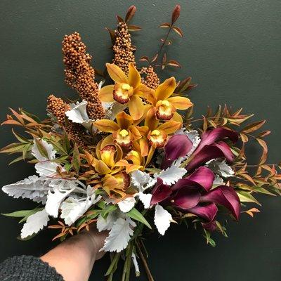 Sophisticated Autumn palette of golden orchids and burgundy calla lilies mixed with Fall accent greenery.