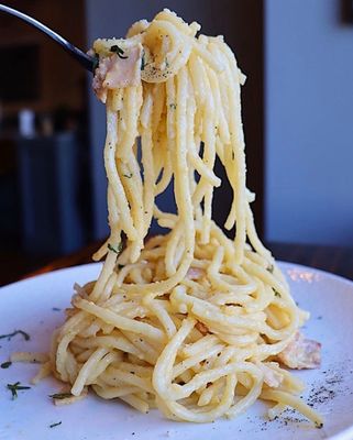 Classic spaghetti carbonara with egg yolk sauce and crispy guanciale.