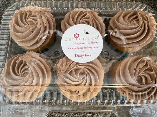 Half dozen vanilla cupcakes with chocolate frosting.