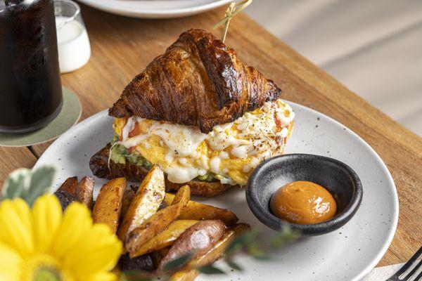 House-made croissant with scrambled free-range eggs, shredded mozzarella cheese, chipotle guava aioli, confit cherry tomatoes, and avocado.