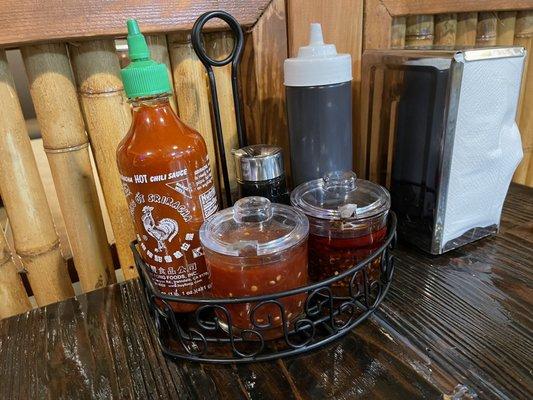 Table condiments: sambal, chili oil, sriracha, soy sauce, hoisin sauce