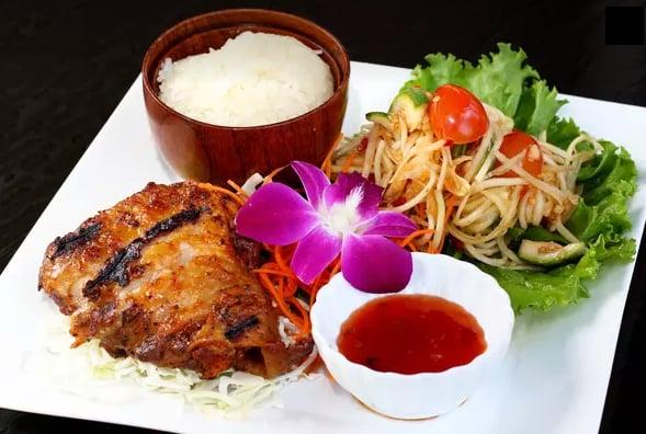 Grilled Five Spice Chicken: Marinated chicken thigh with thai herbs served with sweet and sour sauce, papaya salad, and sticky rice