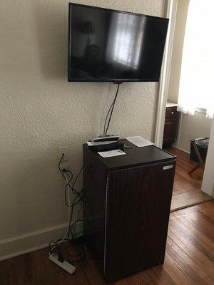 Tiny TV and mini fridge, all cords tangled on the floor