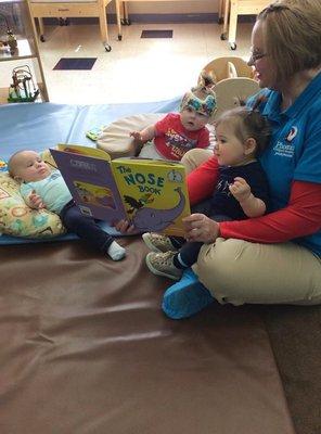 Infants Reading Book with Teacher