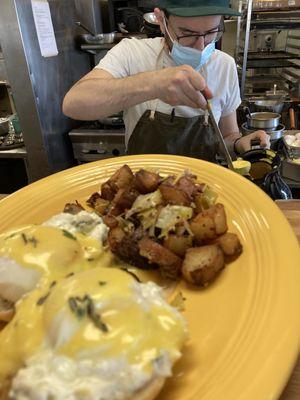 Veggie eggs benedict - poached eggs and hollandaise over creamy kale and artichoke dip on a toasted english muffin with a side of home fries