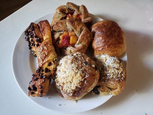 Assortment of pastries including a chocolate croissant, almond croissant, galette and a torsade.