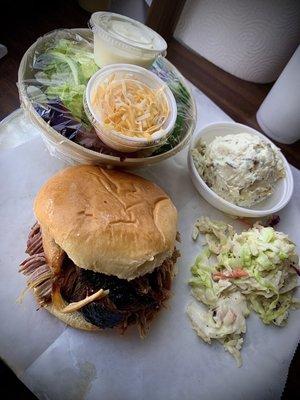 Pulled pork sandwich with slaw, potato salad, and tossed salad.