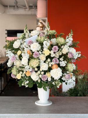 Elegant floral arrangement with white,cream and lavender blooms. Perfect for memorials, funerals or special events.