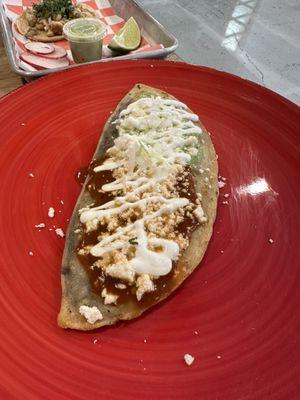 Tlacoyo. First time trying this. It's a soft corn dough filled with beans, flattened, and topped with cheese and sauce. Tasty appetizer.