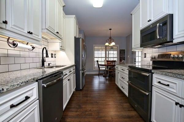 White cabinets, granite countertops, custom lighting and flooring ... another beautiful kitchen remodel by Savvy Home Supply.