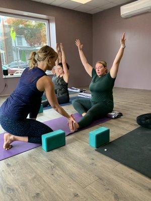 Yoga Home teacher Lori McAlister assist student Kaitlyn in a seated posture.