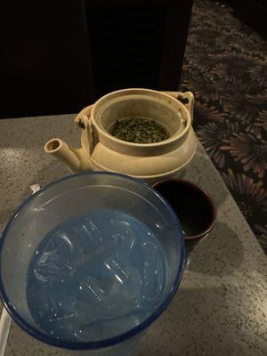 Water and green hot tea served without a lid.