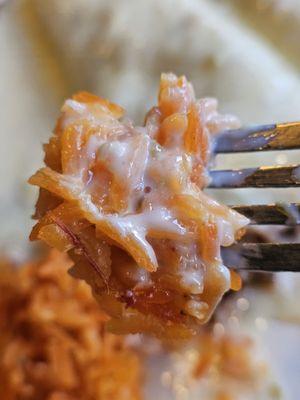 A fork holding some of the red rice with cheese on top.