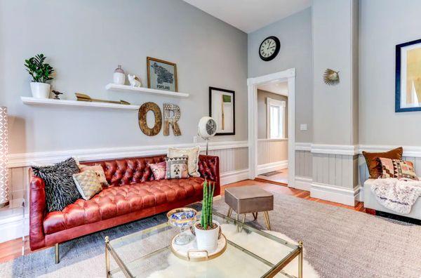 Staged living room with red leather couch and local accessories.