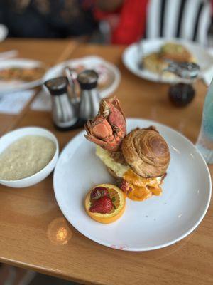 Lobster, egg & cheese croissant with a side of grits.